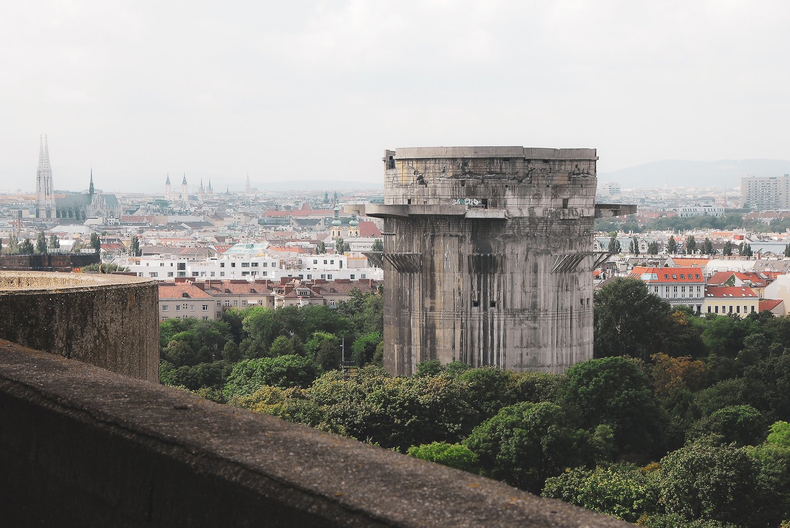 Der ehemalige Flakturm im Wiener Augarten, aufragend über den Baumkronen, im Hintergrund die Innenstadt Wiens.